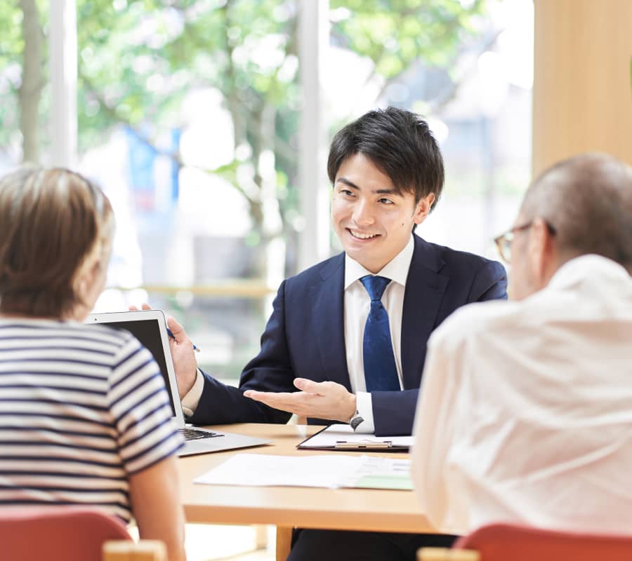 不動産コンサルタントが高齢夫婦にプレゼンテーションしている様子。